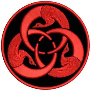 May include: A red, circular patch with a design of three stylized birds intertwined in a circle. The birds are facing inward, with their beaks touching in the center of the circle. The background is black.