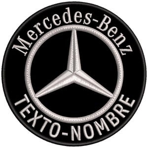 Può includere: Toppa ricamata con il logo Mercedes-Benz. Il design presenta una stella argentata a tre punte all'interno di un anello argentato, su sfondo nero. Le parole "Mercedes-Benz" e "TEXTO-NOMBRE" sono ricamate sul bordo.