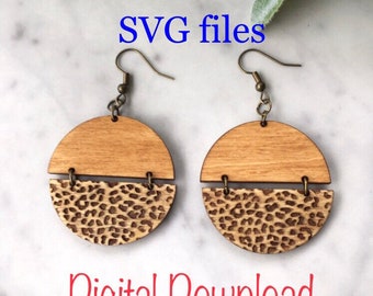 May include: A pair of laser cut wooden earrings with a leopard print design. The earrings are made of two pieces of wood, one with a natural wood finish and the other with a leopard print design. The earrings are attached to gold-colored hooks. The image includes the text "PDF, JPG, SVG files, Digital Download, Laser cut earrings".