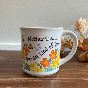 Könnte beinhalten: Eine weiße Keramik-Kaffeetasse mit Blumenmuster und dem Text "Mother is a... special kind of love."
