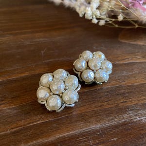 May include: A pair of vintage pearl cluster earrings. Each earring comprises a cluster of faux pearls set on a gold-toned metal base. The earrings are round and have a classic design, ideal for adding a touch of vintage charm to any outfit.