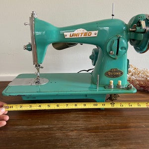 May include: A teal blue vintage United sewing machine with a metal foot pedal and a label that reads "101 De Luxe".