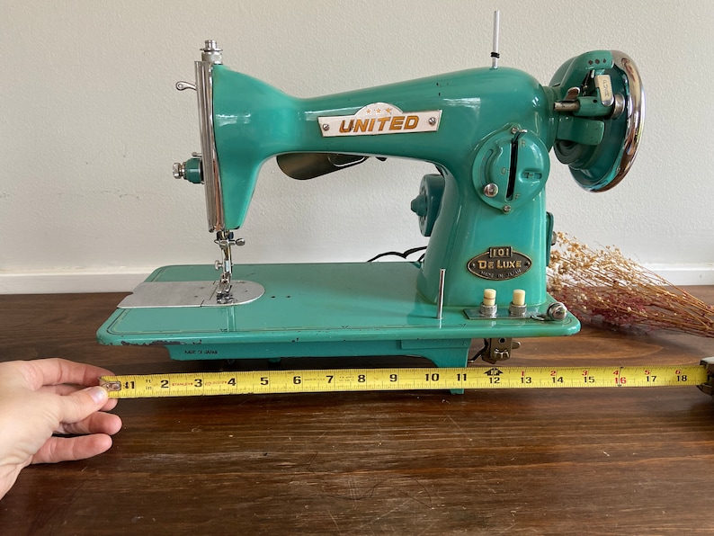 May include: A teal blue vintage United sewing machine with a metal foot pedal and a label that reads "101 De Luxe".