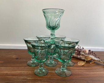 Könnte beinhalten: Satz von sieben grünen Weingläsern aus Glas mit einem Wirbelmuster. Die Gläser sind in Pyramidenform angeordnet, wobei das größte Glas oben liegt.