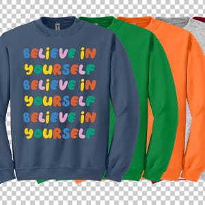 Może przedstawiać: Zestaw pięciu bluz w r&oacute;żnych kolorach, każda z nadrukiem "Believe in Yourself" na przodzie w kolorowych literach.