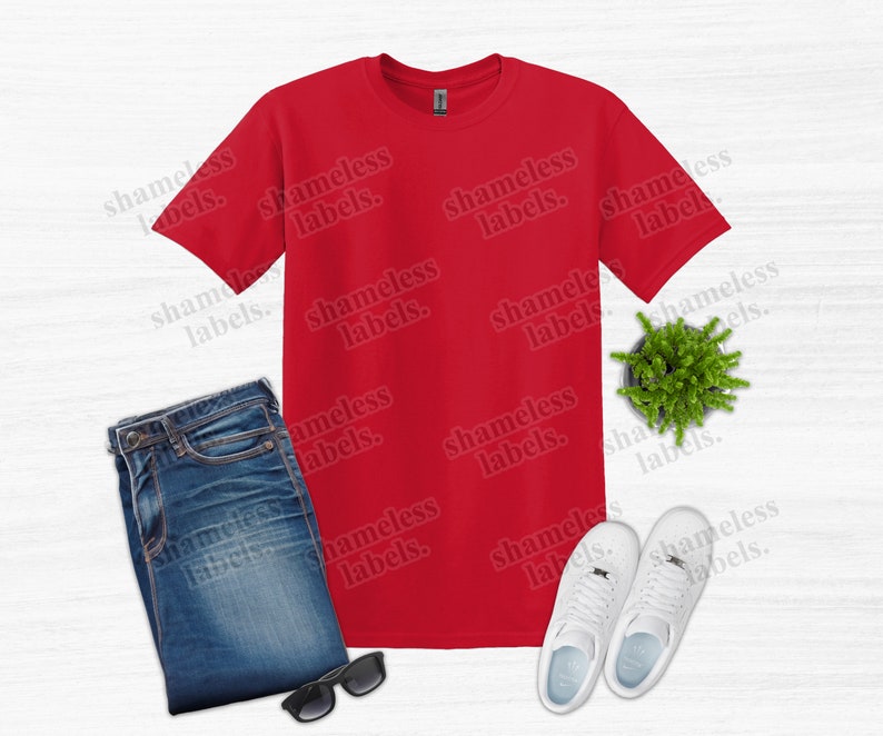 K&ouml;nnte beinhalten: Ein rotes T-Shirt, blaue Jeans, wei&szlig;e Turnschuhe, eine Sonnenbrille und eine kleine Topfpflanze sind auf einer wei&szlig;en Oberfl&auml;che angeordnet. Der Text "shameless labels" wiederholt sich im Bild. Dieses Bild deutet auf ein l&auml;ssiges Outfit hin.