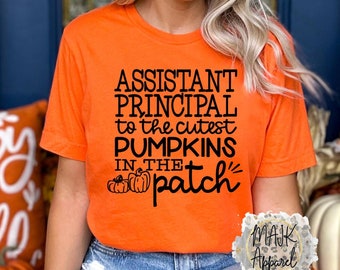 May include: Orange t-shirt with black text that reads "Assistant Principal to the cutest pumpkins in the patch". The shirt features a small graphic of three pumpkins.