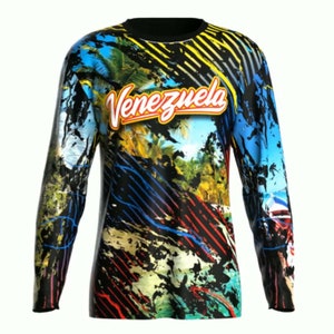 May include: A black long-sleeve shirt with a colorful abstract design featuring palm trees, a beach scene, and the word "Venezuela" in red and yellow letters.