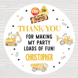 May include: A round sticker with a construction theme. The design includes yellow construction vehicles, road signs, and the text "THANK YOU FOR MAKING MY PARTY LOADS OF FUN!" and the name "CHRISTOPHER".