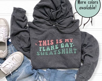 May include: A dark gray hooded sweatshirt with the text "This is my flare day sweatshirt" in pink and green lettering.