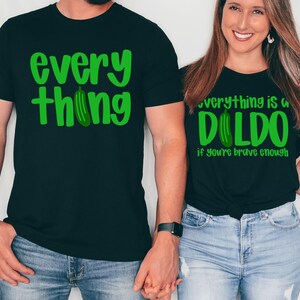 May include: Two black t-shirts with green text and a cucumber graphic. One shirt says "everything thing" and the other says "everything is a dildo if you're brave enough". The shirts are worn by two people.