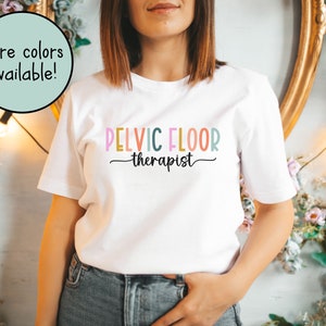 May include: White t-shirt with the text "PELVIC FLOOR therapist" in rainbow colors.