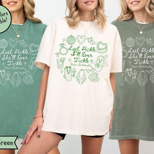 以下が含まれることがあります： ライトグリーン、クリーム、モスグリーンの3枚のTシャツ。各シャツには、「Last Pickle She'll Ever Tickle」と「Katie's Bachelorette」の文字と、ピクルスと結婚をテーマにしたイラストが描かれた白いグラフィックが施されています。「More colors available!」の文字が円で囲まれています。
