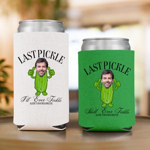 Op de afbeelding: Twee blikjeskoelers, één gebroken wit en één groen, met een zilveren bovenkant. Elke koeler heeft de tekst "LAST PICKLE" boven een cartoon augurk met het gezicht van een persoon. De gebroken witte koeler zegt "I'll Ever Tickle".