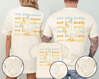 Könnte beinhalten: Cremefarbene T-Shirts mit einer skurrilen Gänsegrafik, die eine Partyhütchen trägt und ein Geschenk hält. Auf den Shirts steht "one silly mama", "one silly daddy" und "one silly goose". Ein lustiges, familienorientiertes Bekleidungsset.