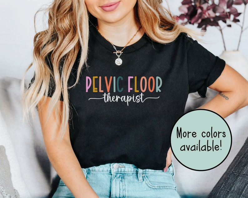 May include: Black t-shirt with the text "Pelvic Floor Therapist" in colorful letters. The text is written in a playful, casual font.  More colors are available.
