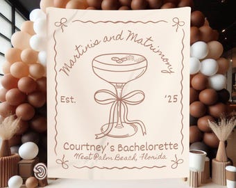 Könnte beinhalten: Ein beigefarbenes Stoffbanner mit braunem Text, der "Martini's and Matrimony Est. '25" lautet, mit einer Strichzeichnung eines Martini-Glases mit Schleife. Der Text "Courtney's Bachelorette West Palm Beach, Florida" steht ebenfalls auf dem Banner.
