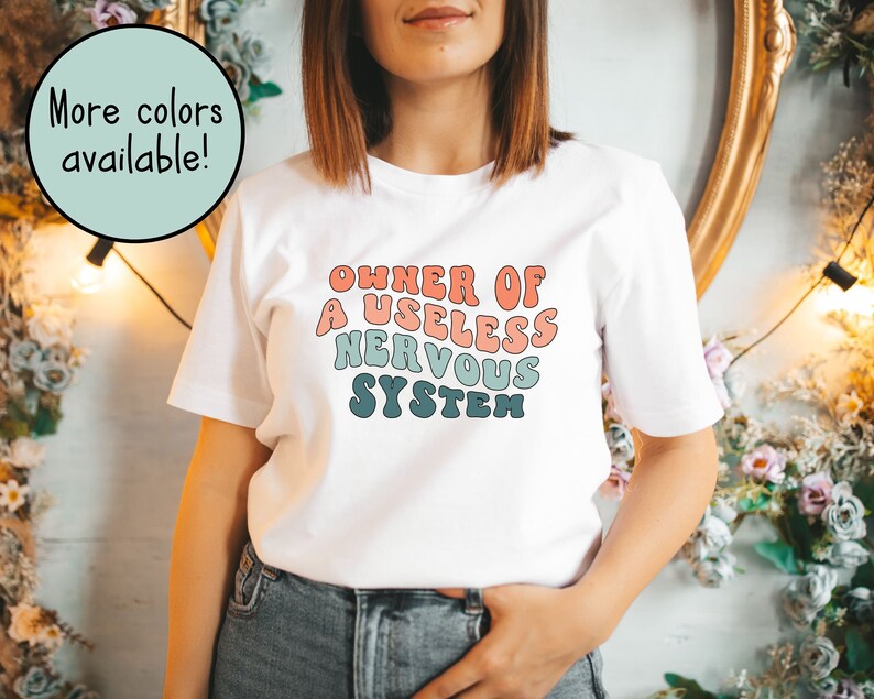 May include: White t-shirt with a colorful graphic that reads "OWNER OF A USELESS NERVOUS SYSTEM".
