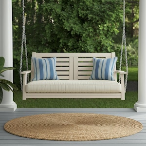 May include: A white wooden swing bench with blue and white striped cushions hanging from a chain on a porch with a brown woven rug.