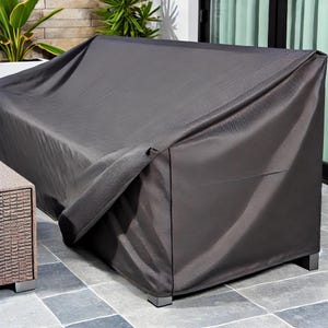 High-quality dark grey cover, tightly fitted over an outdoor sofa set. The water-resistant fabric offers protection from the elements, with a stone patio and potted plants completing the elegant, functional outdoor setting.