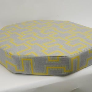 May include: A gray and yellow octagonal cushion with a geometric pattern.