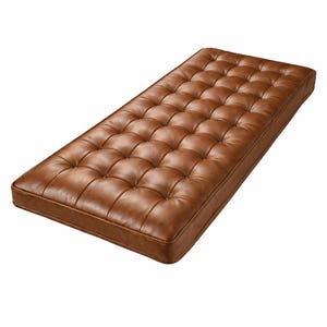 May include: A rectangular bench cushion upholstered in smooth, medium-brown leather. The top surface features a consistent tufted pattern with recessed buttons arranged in a grid, creating a quilted appearance with defined edges and corners.