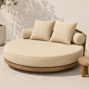 May include: A circular outdoor daybed with a natural wood frame and beige fabric upholstery. The piece includes two square throw pillows and two cylindrical bolster pillows in the same matching beige fabric, arranged on a round cushioned base.