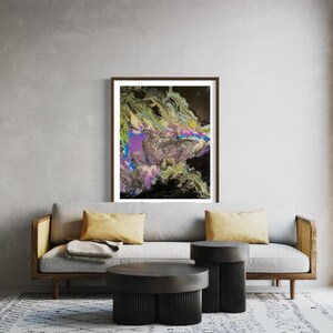 May include: Abstract art print in a brown frame. The artwork features a vibrant mix of colors, including purple, green, yellow, and black, creating a dynamic and textured composition. The print is displayed above a gray sofa with yellow pillows.