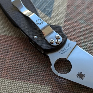 Può includere: Un coltellino tascabile nero e argento con un logo Spyderco e il testo "Spyderco CPM S45VN" sulla lama.
