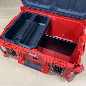 May include: An open red Milwaukee Packout tool box with a black interior. The box has a removable divider and a large compartment.