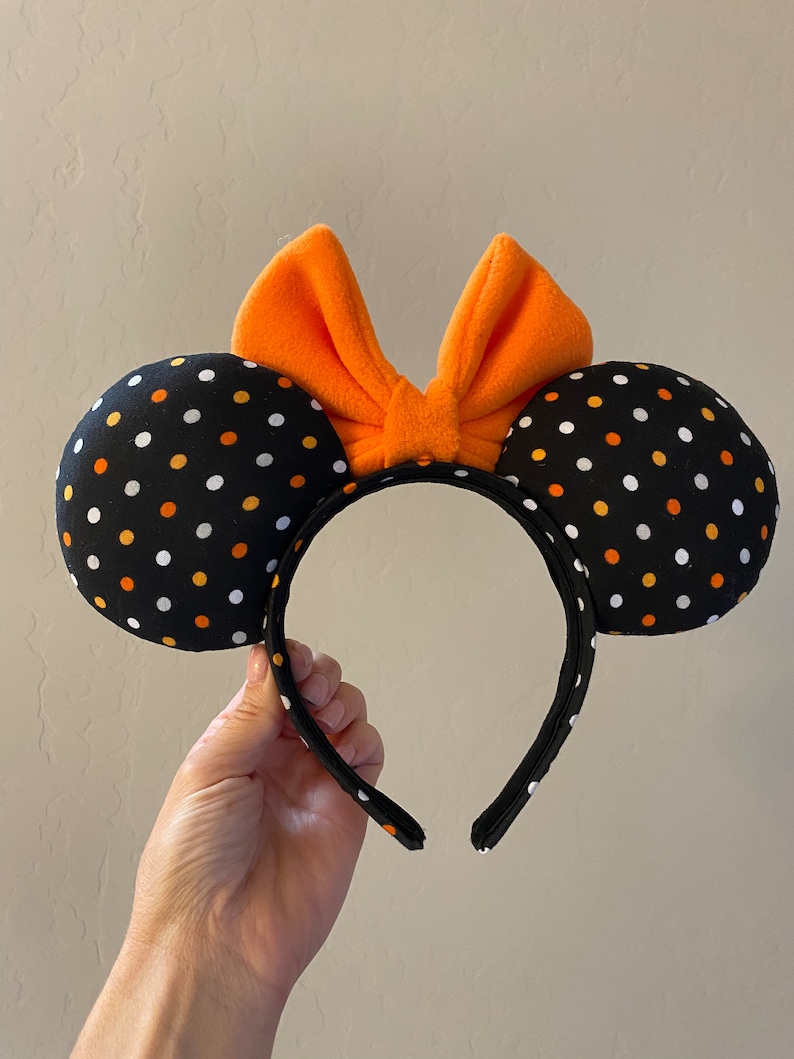 May include: Black and orange polka dot Minnie Mouse ears with an orange bow.