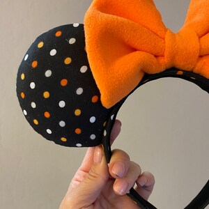 May include: Black headband with orange and white polka dot fabric mouse ears and a large orange bow.