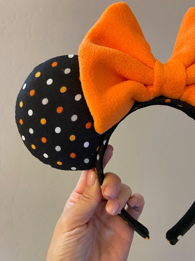 May include: Black headband with orange and white polka dot fabric mouse ears and a large orange bow.