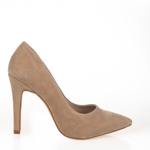 May include: A pair of beige suede high-heeled pumps with a pointed toe.