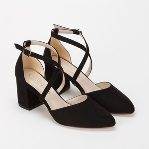 Puede incluir: Zapatos de tac&oacute;n de ante negro con tiras cruzadas y tac&oacute;n de bloque.