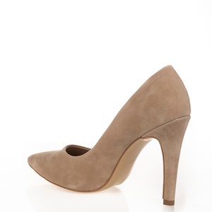 May include: A pair of beige suede high-heeled pumps with a pointed toe.