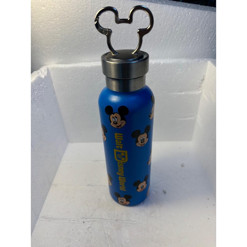 May include: Blue stainless steel water bottle with a Mickey Mouse design and a Mickey Mouse shaped lid. The bottle has the text "Walt Disney World" on the side.