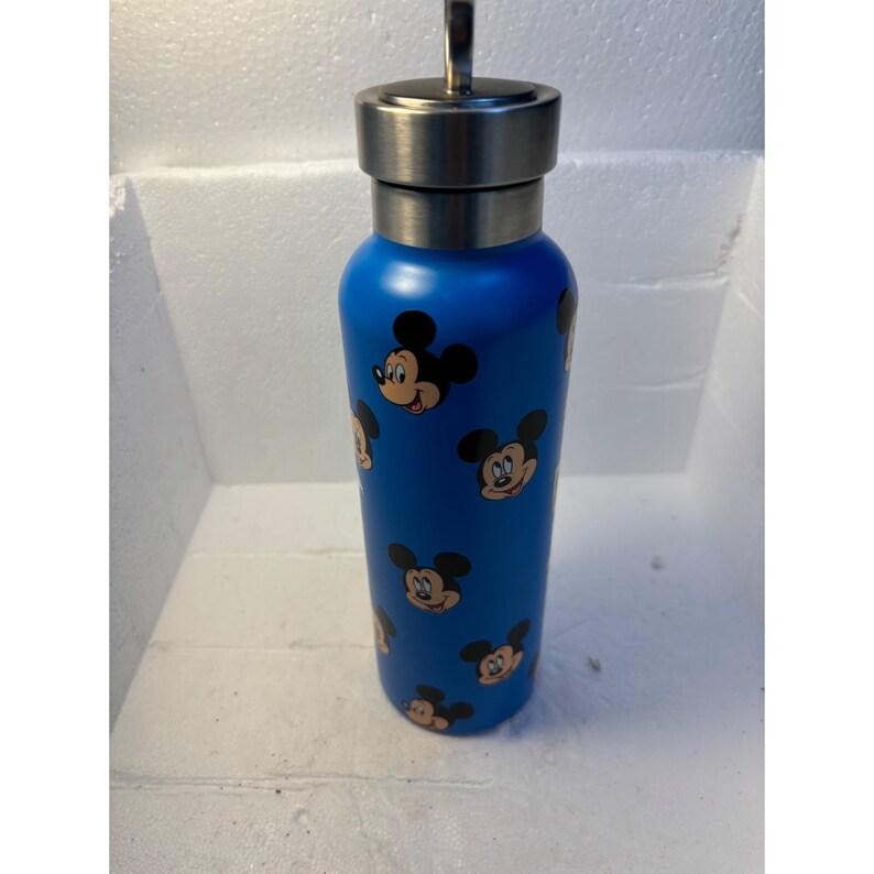 May include: A blue stainless steel water bottle with a Mickey Mouse pattern. The bottle has a silver lid with a loop on top.
