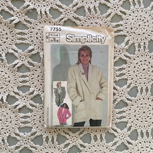 Könnte beinhalten: Ein Vintage-Schnittmuster von Simplicity, Nummer 7755, mit einer Frau in einem beigen Blazer. Das Muster enthält Bilder verschiedener Blazer-Stile. Das Muster liegt auf einem cremefarbenen, offen gewebten Textil.