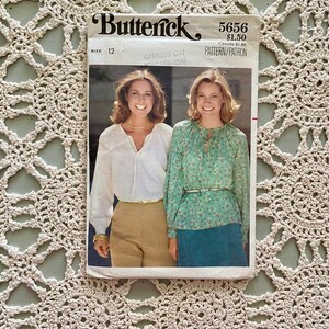 Puede incluir: Patrón de costura vintage para dos blusas, Butterick 5656, talla 12. El patrón presenta a dos mujeres usando las blusas, una en blanco y la otra con estampado floral.