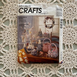 May include: A vintage McCall's Crafts sewing pattern for springtime decorations. The pattern includes instructions for making a wreath, baskets, and bunny figurines. The pattern number is 5225.