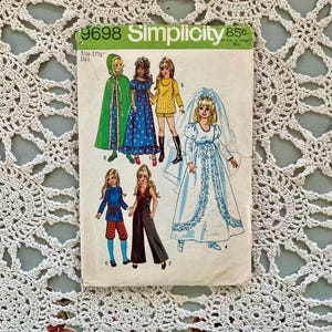 Pode incluir: Padrão de costura Simplicity vintage 9698 para uma boneca de 44,5 cm. O padrão apresenta ilustrações de várias roupas de bonecas, incluindo uma capa com capuz verde, um vestido floral azul, um vestido amarelo, um vestido de noiva e outras roupas.
