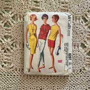 May include: A vintage McCall's sewing pattern for a misses' sports separates outfit. The pattern includes an overblouse, skirt, trousers in two lengths, and a scarf. The pattern number is 6207 and the size is 12, bust 32. The pattern is printed on a yellow background with a black and white illustration of three women wearing the different pieces of the outfit.