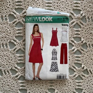 Peut inclure: Un patron de couture pour une robe rouge et un haut et une jupe à motifs blancs et noirs. Le patron est de New Look et est étiqueté "facile".