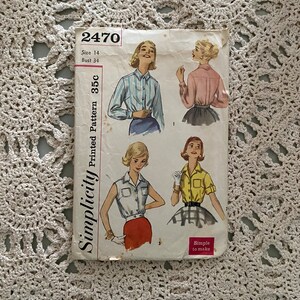 Puede incluir: Patrón de costura vintage Simplicity número 2470 para una blusa. El patrón es para la talla 14, busto 86 cm y cuesta 35 centavos. El patrón muestra tres estilos diferentes de blusas, una con mangas largas, una con mangas cortas y una sin mangas.