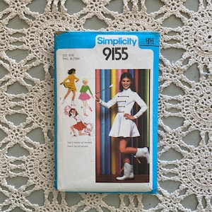 Puede incluir: Un patrón de costura Simplicity vintage, número 9155, con ilustraciones de jóvenes en varios atuendos. La portada es azul y blanca, con el logotipo de Simplicity e información de tallas. Incluye el texto "SIZE 9/10 YNG. JR/TEEN".