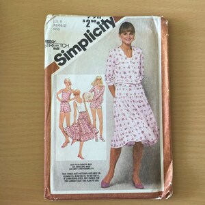 May include: A Simplicity sewing pattern for a skirt and top. The pattern is for sizes 8, 10, and 12. The pattern is for knit fabrics. The pattern shows a woman wearing a floral print skirt and top.