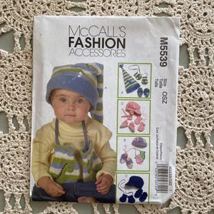May include: A sewing pattern for a baby hat, mittens, and booties. The pattern is for sizes OSZ and includes instructions for making a blue and green hat, a pink and green hat, and a blue hat with matching mittens and booties.