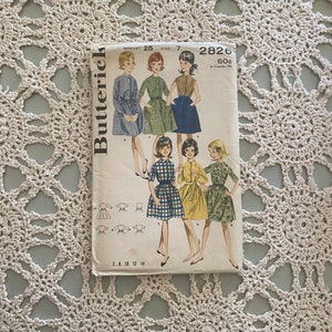 May include: A vintage sewing pattern for a dress, Butterick pattern number 2826, size 7, bust 25 inches. The pattern features a dress with a Peter Pan collar and short sleeves. The pattern is printed on a white background with black text and illustrations of the dress.