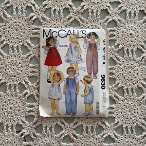 May include: A vintage McCall's sewing pattern for a toddler's outfit. The pattern includes a dress, overalls, and a shirt. The pattern number is 9630 and the sizes are toddler sizes. The pattern is printed on a white background with black text.